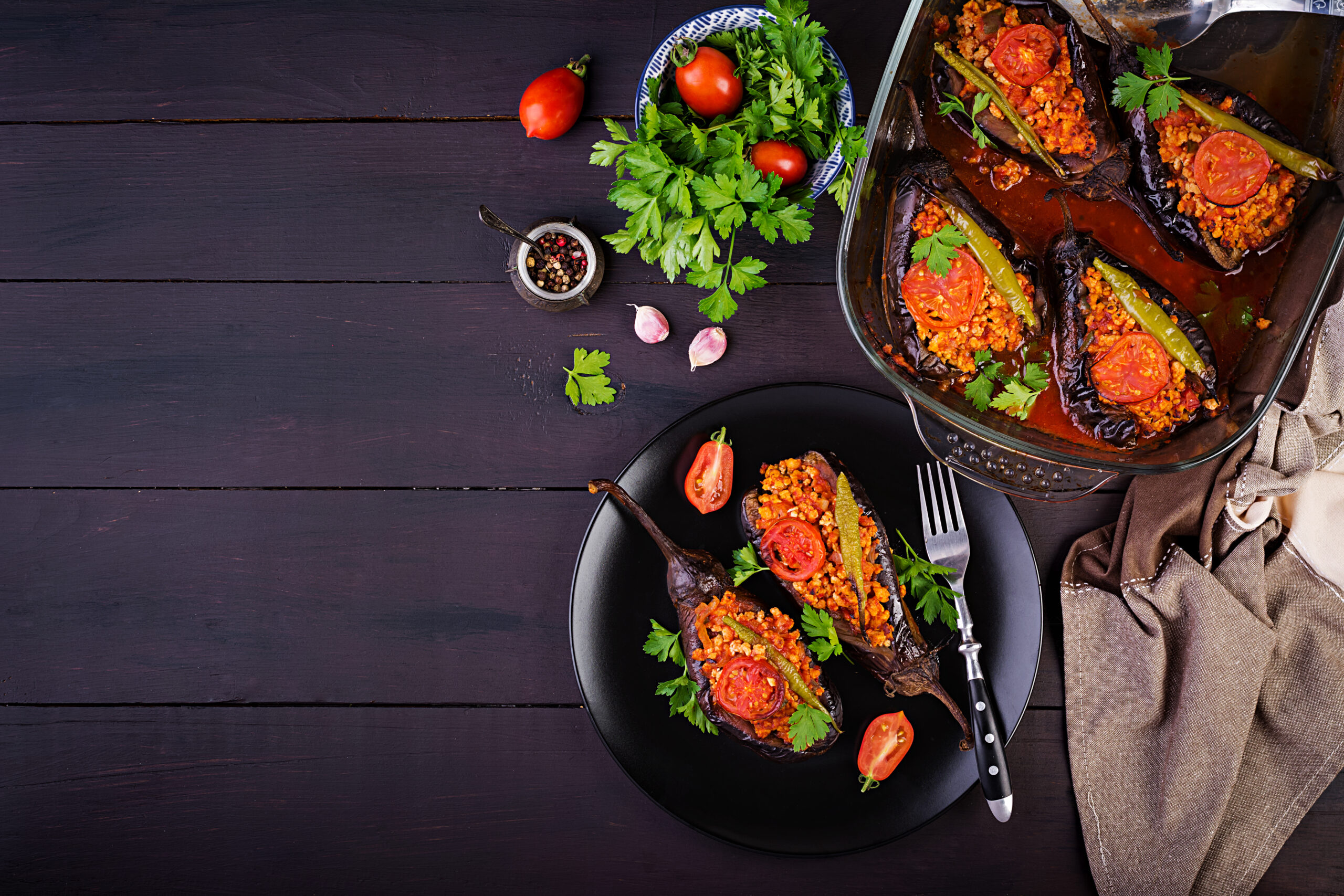 Karniyarik - turkish traditional aubergine eggplant meal. Stuffed eggplants with ground beef and vegetables baked with tomato sauce. Turkish cuisine. Top view. Copy space